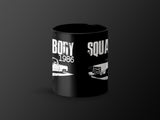 Black mug with white graphic of "Body Square 1986" and two trucks.